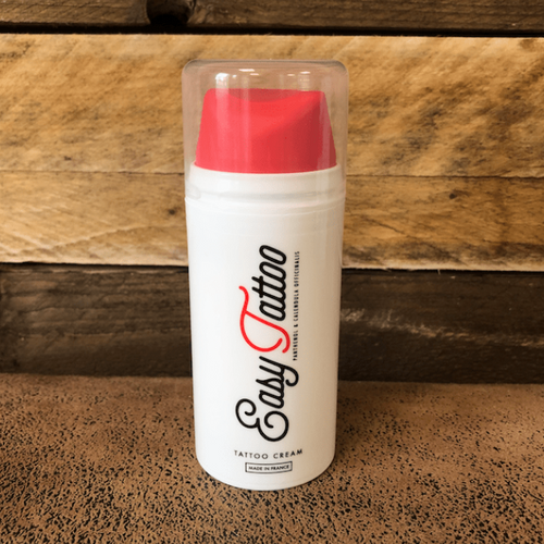 easy tattoo cream aftercare container with red cap on a wooden surface